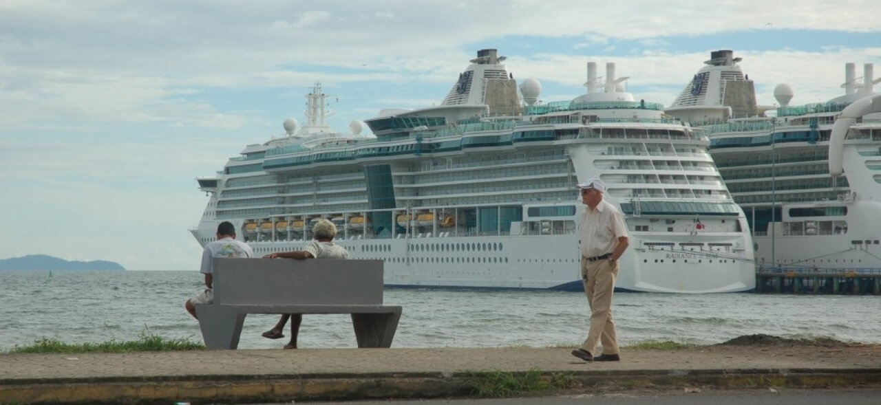 Old man walking in Puntarenas Port with a Cruice behind him. Photo by Héctor Vides / Social Media Costa Rica